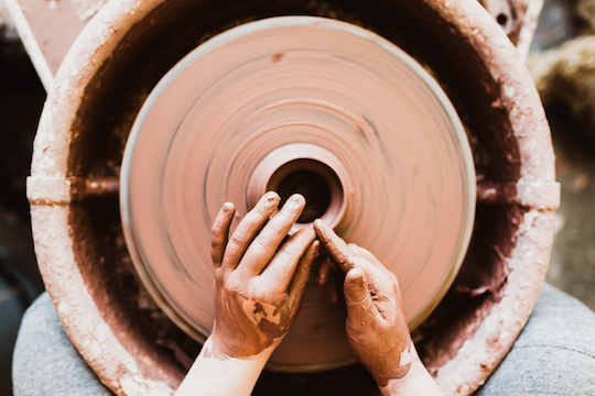 Image of hands shaping a pot on a pottery wheel
